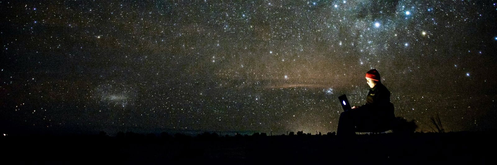 Person on laptop under stars